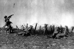 an old black and white photo of soldiers on the ground in front of a fence