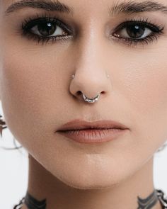 a woman with piercings on her nose looking at the camera while wearing a choker