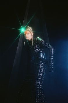 a woman in a black outfit with green lights on her head and hands behind her back