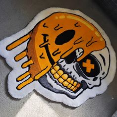 a sticker with a skull wearing a yellow helmet on it's head and an orange cross in the middle