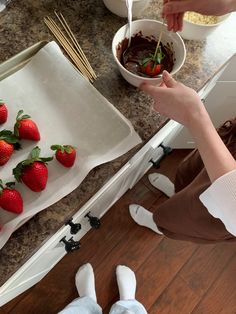 a person is eating strawberries on the kitchen counter with chocolate sauce and strawberries