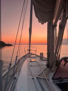 the sun is setting on a sailboat in the ocean