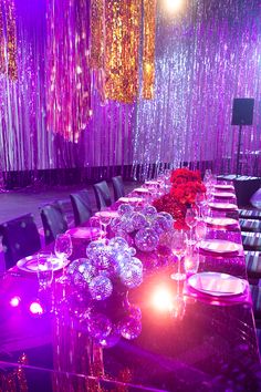 a long table is set up with purple and red lights in the background for a party