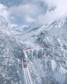 a red train traveling over a snow covered mountain