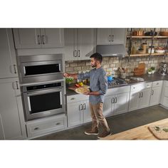 a man is standing in the kitchen with his hand out to grab something from the oven