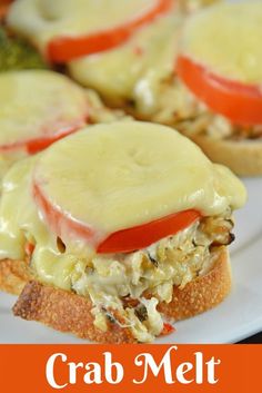 crab meat sandwich with cheese and tomatoes on it is served on a white platter