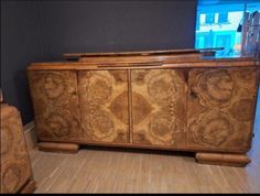 a large wooden cabinet with carvings on the front and sides, sitting in a room next to a window