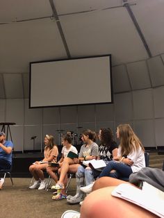 a group of people sitting in front of a projector screen