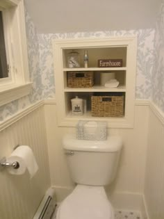 a white toilet sitting inside of a bathroom next to a shelf filled with towels and other items