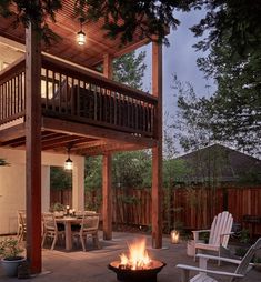 a fire pit sitting in the middle of a patio next to a wooden deck with chairs