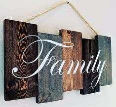 three wooden signs hanging on a wall with the word family written in white ink and wood planks