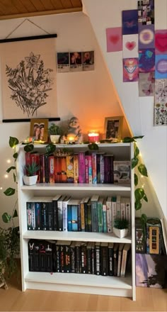 a bookshelf filled with lots of books next to a stair case covered in pictures