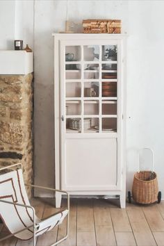 a white cabinet sitting next to a brick wall in a room with wooden floors and walls