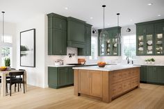 a large kitchen with green cabinets and white counter tops