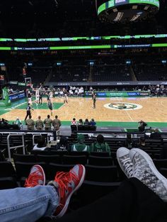 people sitting in the bleachers at a basketball game with their feet on the floor