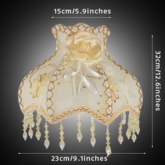 an image of a white lamp shade with gold trimmings and flowers on it