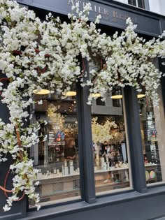 a store front decorated with white flowers and greenery