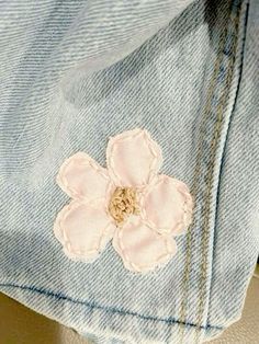 a pink flower is on the back of a jean jacket