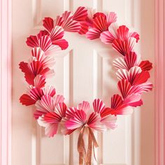 a wreath made out of pink paper sitting on top of a door