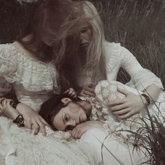 two women are laying in the grass with their heads on each other's shoulders