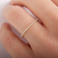 a woman's hand with a wedding band on it, and the ring is in gold