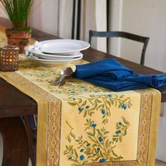 the table is set with plates, silverware and blue napkins on top of it