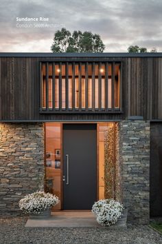 an entrance to a modern home with stone and wood