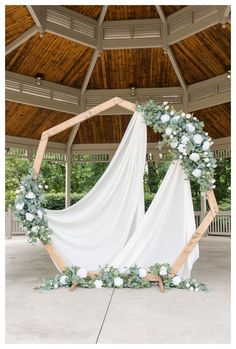 a wedding arch decorated with white flowers and greenery