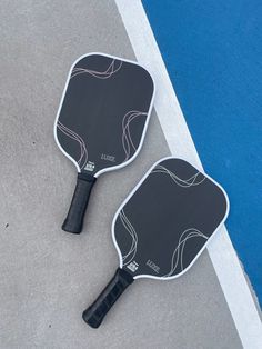 two ping pong paddles laying on the ground next to each other in front of a blue wall