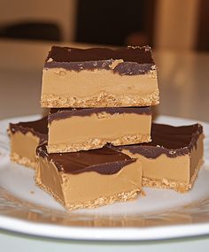 three pieces of chocolate peanut butter bars stacked on top of each other in front of a plate