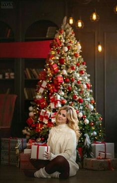 a woman sitting in front of a christmas tree