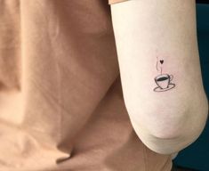 a woman's arm with a coffee cup tattoo on the left side of her arm