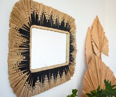 there is a mirror made out of straws on the wall next to a potted plant