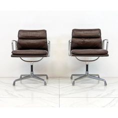 two brown leather office chairs sitting next to each other on top of a white floor