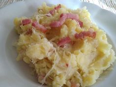 a white plate topped with mashed potatoes and bacon