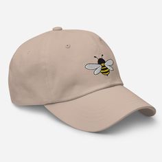 a baseball cap with a bee embroidered on the front and back side, in beige