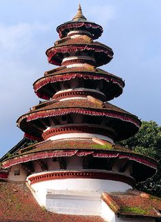 a tall white and red building sitting on top of a lush green field