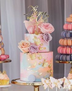 there is a multi layer cake with pink flowers on the top and gold decorations around it