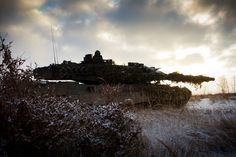 an old tank sitting in the middle of a field with snow on it's ground