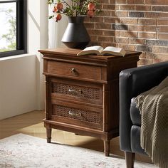 an open book sits on top of a wooden cabinet in front of a brick wall