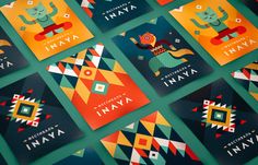 many colorful posters are arranged in rows on a green surface, with the words inaya written above them