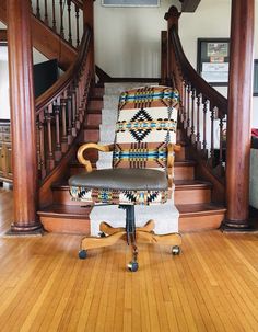 an office chair sitting on top of a wooden floor next to a stair case in a home