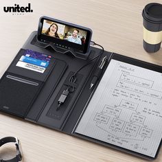 an open notebook with a cell phone on top of it next to a coffee cup