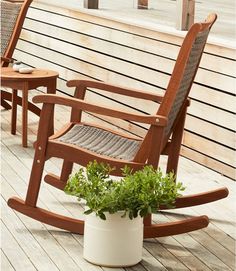 two wooden rocking chairs sitting on top of a wooden deck next to a potted plant