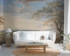 a living room with a white couch and painting on the wall behind it, in front of a window