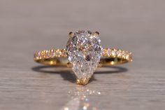 a pear shaped diamond ring on a wooden surface