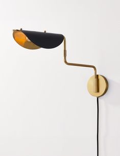 a black and gold wall light on a white wall next to a brown lamp shade