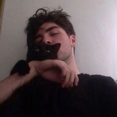 a man taking a selfie in front of a mirror with a cat on his face