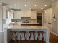 a kitchen with three stools in front of an island