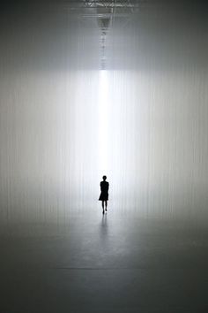 a person is standing in the middle of a dark room with light coming through it